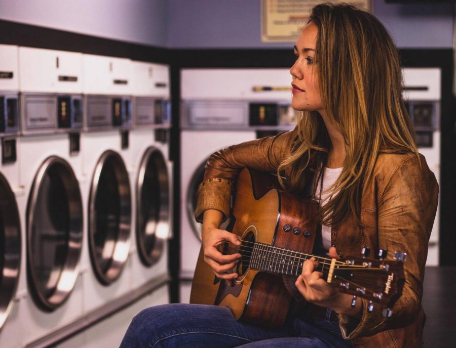 Mackenzie OBrien poses for a publicity photo while playing guitar.