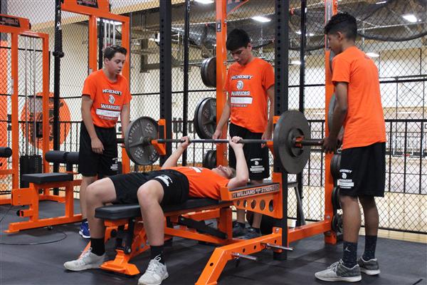 (L-R) Evan Cummings, Tyler Thomas, and Enrique Ravelo assist their classmate during a lifting session.
