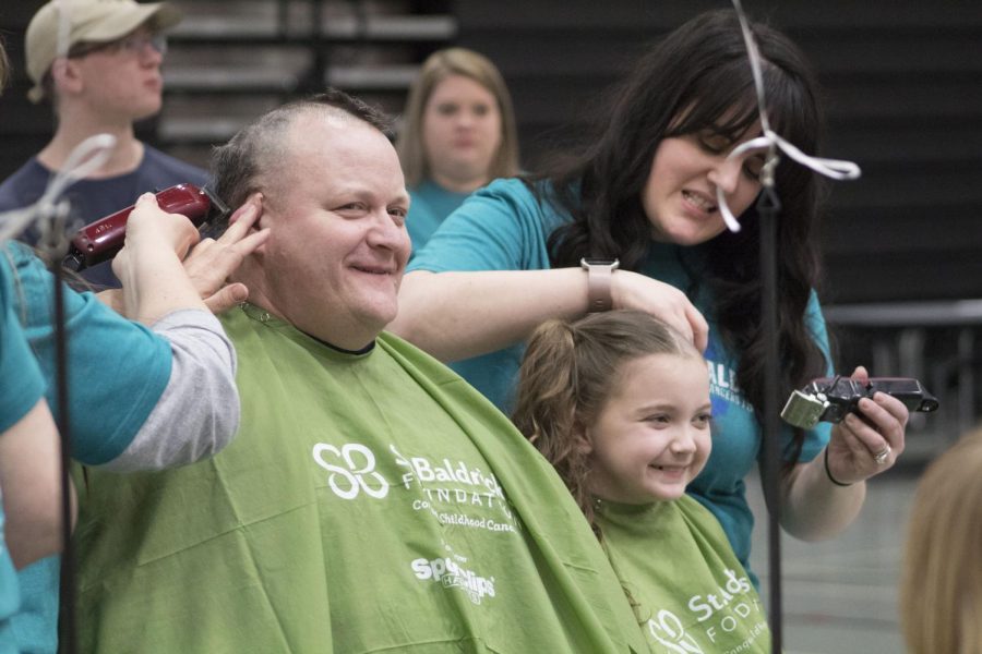 Carl Vallianatos, assistant superintendent of curriculum and instruction, has his head shaved alongside his daughter Sophie during the 2019 Community Shave in the West Campus Main Gym on March 21.