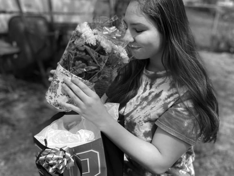 Adopted senior Sydni Johns opens a care package from Linnea Schwartz in her front yard on May 7. John is one of dozens of seniors adopted by the community as their senior year ends during a state-wide shelter-in-place order.