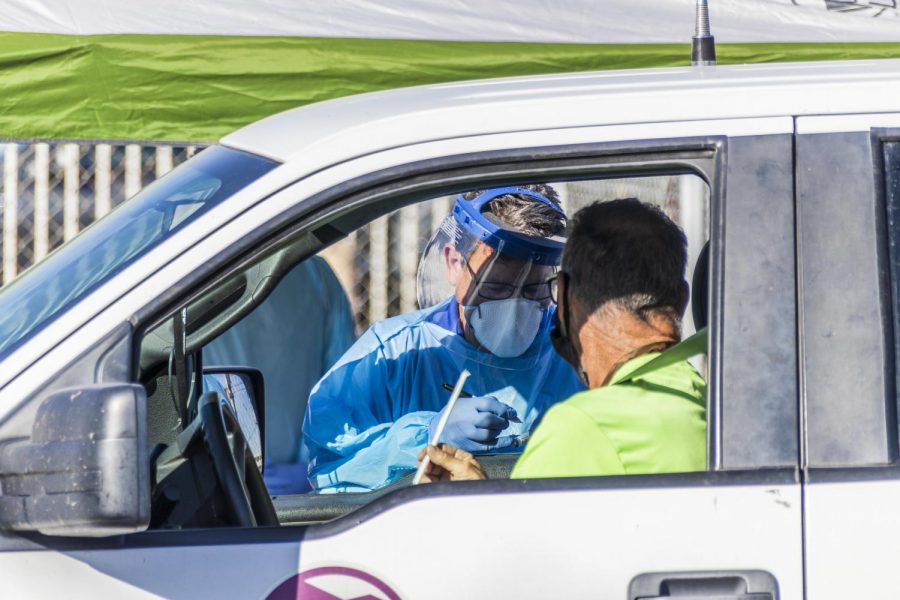 Health care workers collect saliva samples at a drive-up testing site in Arizona in November. Since then, COVID cases have dropped significantly in most states, including Illinois.