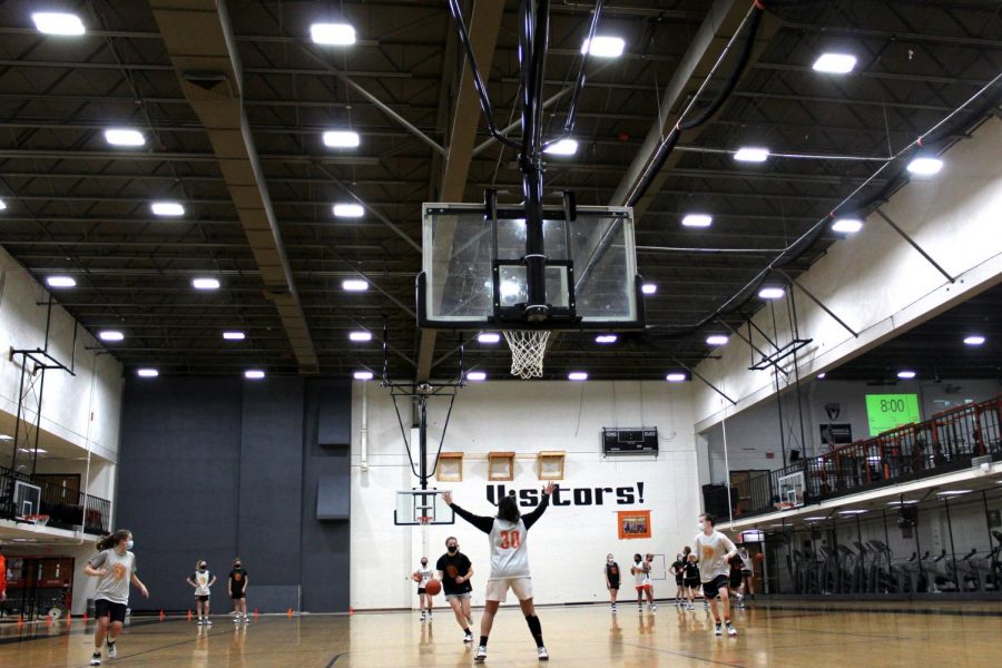 The girls basketball team practices in Buckner Gym at West Campus on March 3 while other athletes train in the weight room. Two- and three-season athletes have had to make tough decisions about which sports to play — and which not to play — during overlapping seasons.