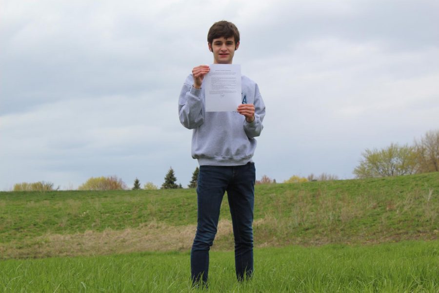 Freshman Daniel Thomas stands outside of West Campus with his Greentastic climate agreement. Thomas penned the agreement with environmental club in an attempt to make a positive change at MCHS.