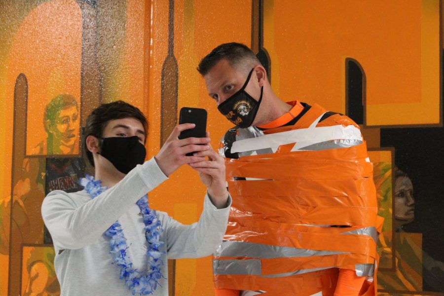 Students pose with Derek Galvicius during Duct Tape the Teacher, which concluded Homecoming week on April 23 outside the West Campus cafeteria.