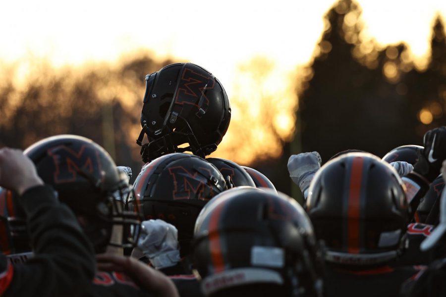 The varsity football team huddles before a home game and stokes their team spirit against Huntley at McCracken Field on April 1. Several senior athletes at MCHS, including football players, intend to play college-level sports next year.