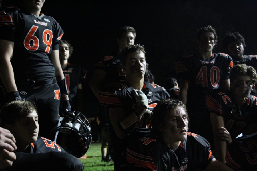 The varsity football team meets in the shadows behind the stadium during halftime at the first home game of the season on September 3 at McCracken Field.