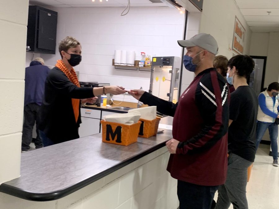 Working on behalf of National Honor Society, business teacher Erin Harris gives change while working the concession stand during the varsity girls basketball game on Dec. 3 outside the Upper Campus Main Gym.