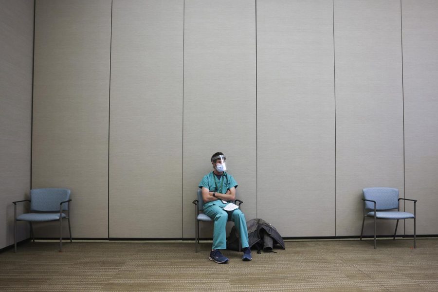Rocky Mountain Regional VA Medical Center internal medicine resident Luc Overholt sits in a waiting area before receiving a dose of the Pfizer-BioNTech COVID-19 vaccine at the hospital on Dec. 16, 2020, in Aurora, Colorado.