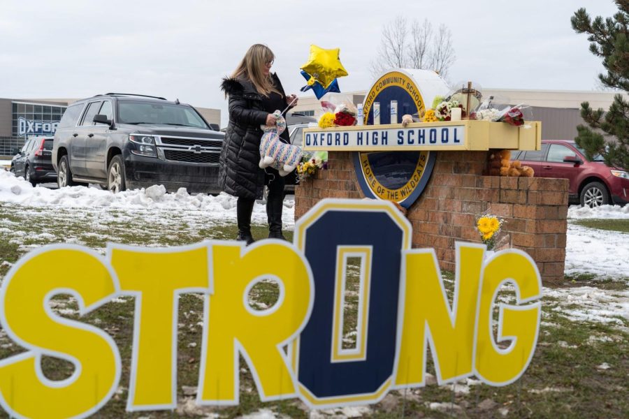 A woman leaves a stuffed animal at a memorial at an entrance to Oxford High School on Dec. 1, following an active shooter situation at Oxford High School that left four students dead and multiple others with injuries.