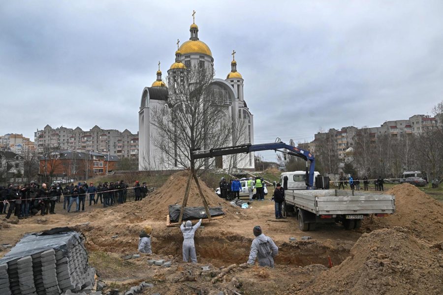 Journalists gather as bodies are exhumed from a mass-grave in the grounds of the St. Andrew and Pyervozvannoho All Saints church in the Ukrainian town of Bucha, northwest of Kyiv on April 13, 2022.