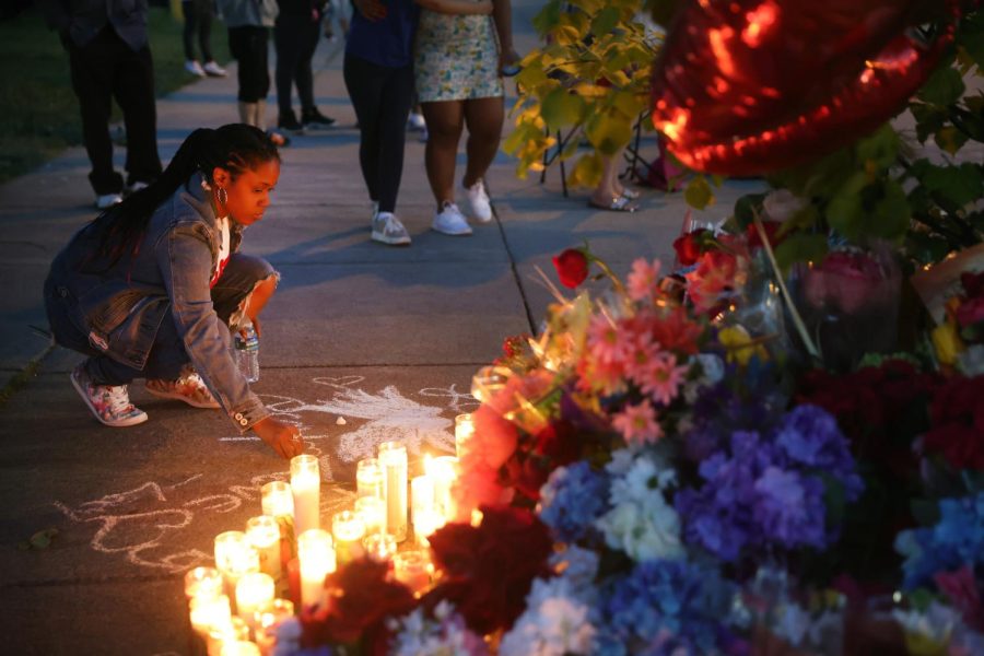 A woman chalks a message at a makeshift memorial outside of Tops market on May 15, 2022 in Buffalo, New York. A gunman opened fire at the store yesterday killing ten people and wounding another three. 