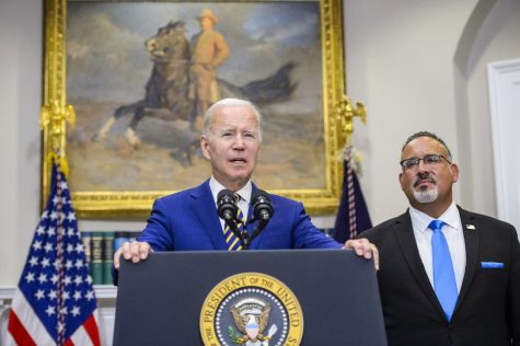 President Joe Biden speaks as Secretary of Education Miguel Cardona looks on after Biden announced a federal student loan relief plan that includes forgiving up to $20,000 for some borrowers and extending the payment freeze in the Roosevelt Room at the White House in Washington, D.C., on Wednesday, Aug. 24, 2022.