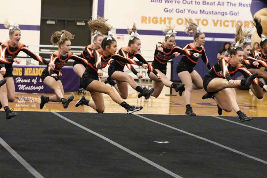 The varsity cheerleading team leaps in the air during a performance at Rolling Meadows High School on Dec. 7.