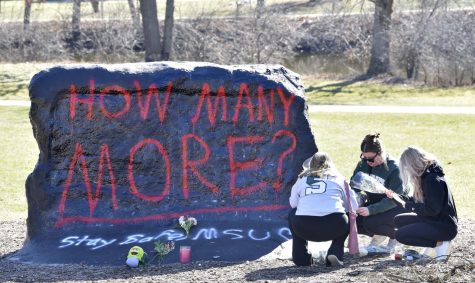 From left, Ella Huff, of Grand Rapids, joins fellow Michigan State University students Sophie Apple and her sister, Abbey Apple, both of Washington Township, as they place flowers at The Rock, on Feb. 14, 2023, the day after a gunman killed three students and injured five others in a shooting on campus.