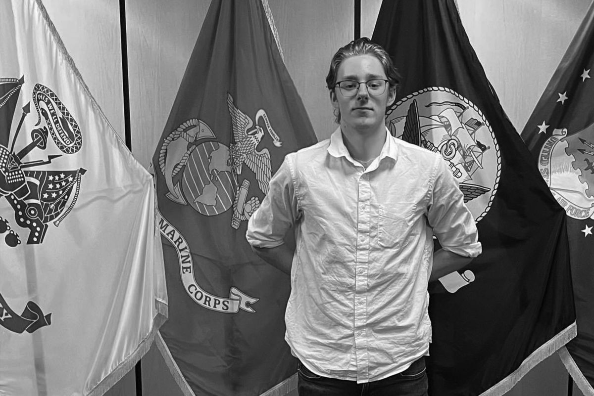 Raymond Wilkinson stands before military flags after enlisting into the U.S. Marine Corps Delayed Entry Program on Sept. 12.