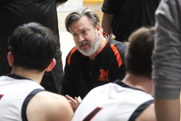 Varsity boys basketball coach Corky Card talks to the team during a time out on Jan. 19 in the Upper Campus main gym during a game against Jacobs.