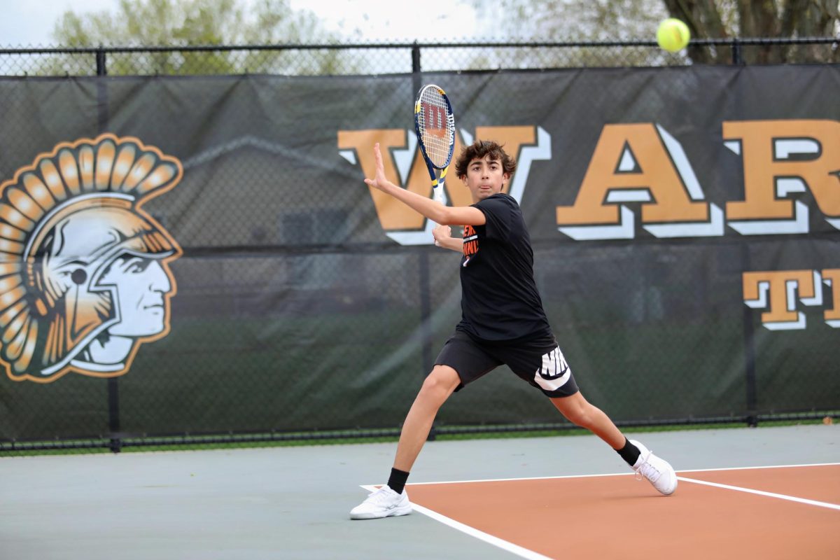 A MCHS tennis player winds up to hit the ball during a boys tennis match on April 14 at the Upper Campus tennis courts.
