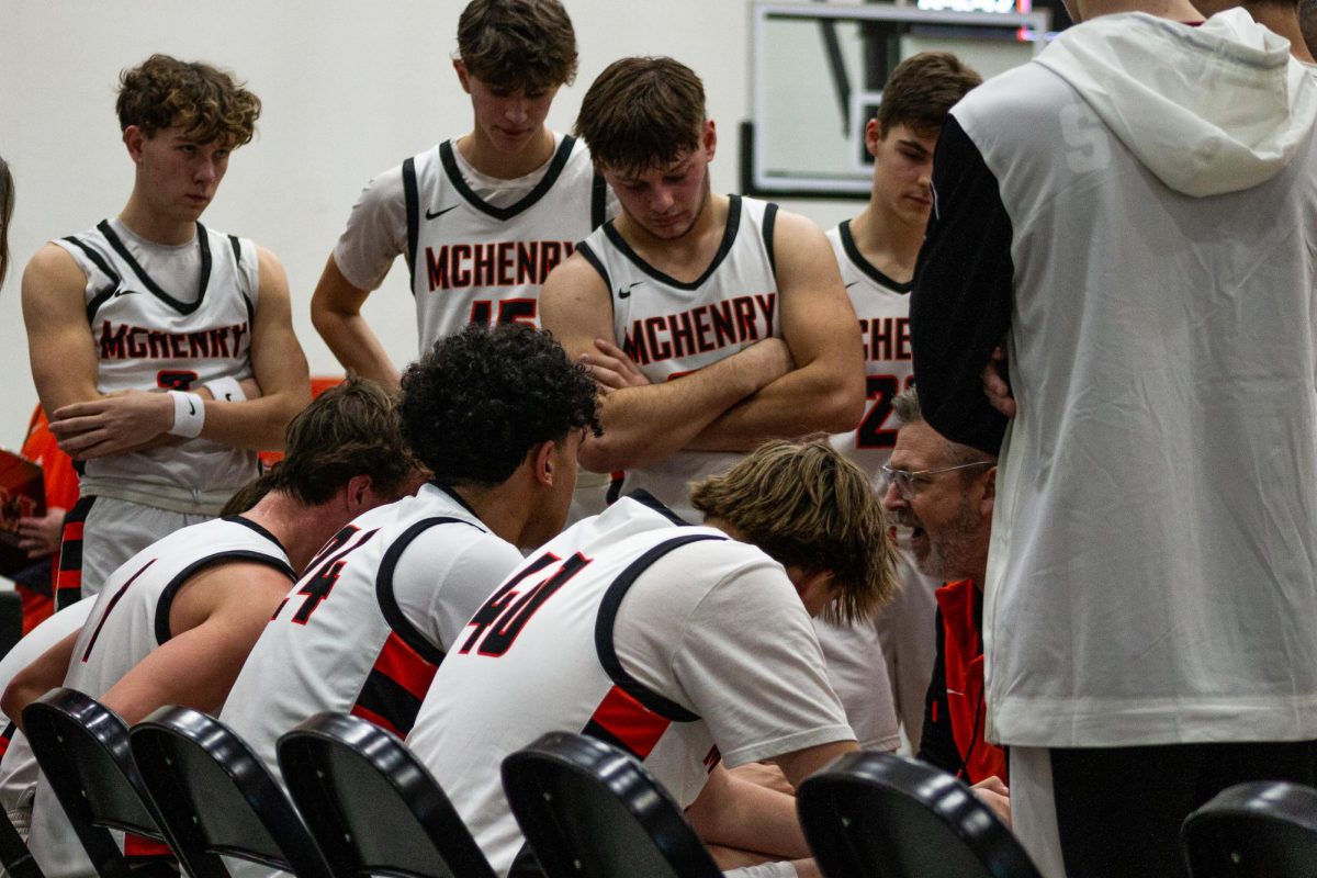 Players on the varsity boys basketball team  a huddle on the sidelines during their game against Crystal Lake South on Dec 11 in the Upper Campus Main Gym.