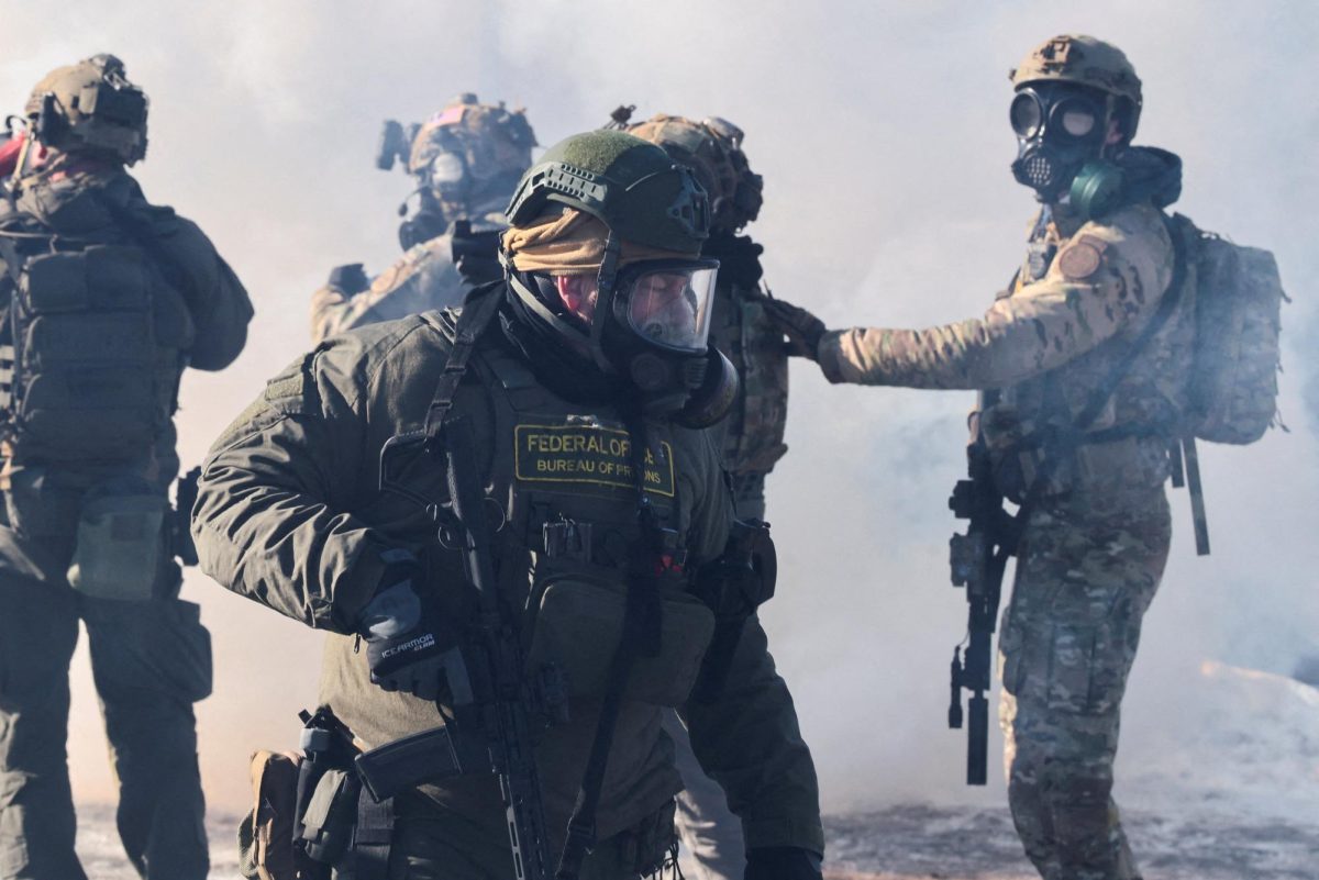 Federal agents stand amid tear gas to disperse people gathered near the scene where federal agents fatally shot a man while trying to detain him, in Minneapolis, Minnesota, U.S., January 24, 2026. REUTERS/Evelyn Hockstein