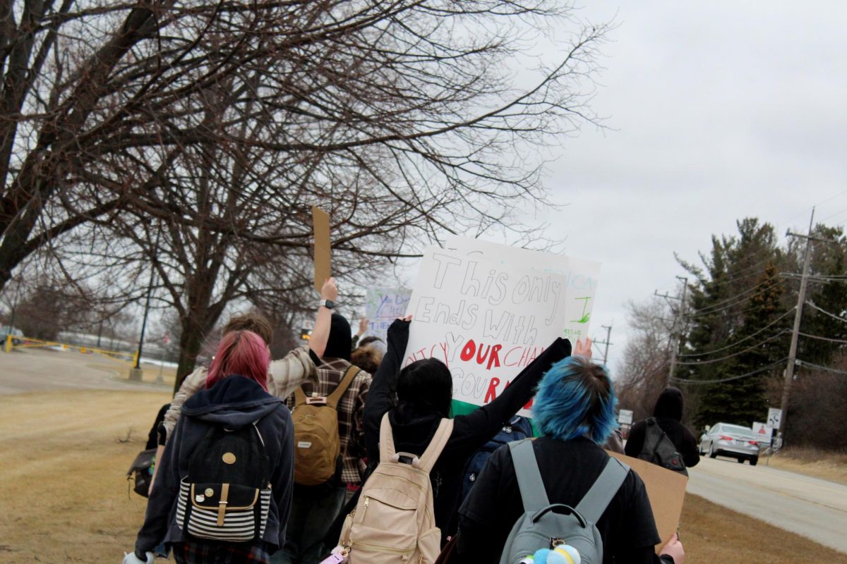 Students carry signs along Crystal Lake Road outside of the Upper Campus during a 6th period walkout on Friday. Students planned the protests against ICE and President Trump for weeks via social media.