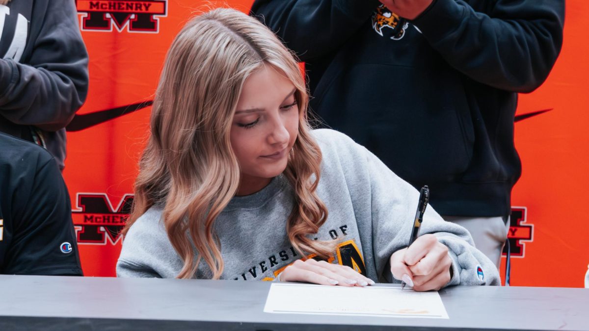 Senior Camille Cohn signs her letter of intent for the University of Iowa for cheerleading int he fall during the signing day ceremony on Wednesday in the Upper Campus main gym.